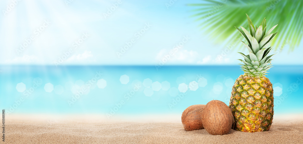 Obraz premium Summer tropical sea with sparkling waves, pineapple and coconuts