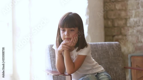 Six years old daughter sit on chair at home feels resent about punishment of parents, kid girl waiting suffer from boredom thinking lost on sad thoughts, little person problems frustrations concept