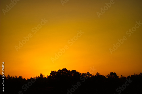 Sunset in the mountains, the silhouette of the woodlands and the orange skies