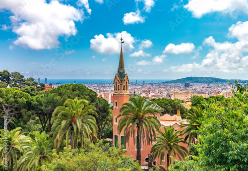 Skyline of Barcelona from the famous Park Guell on a day with blue sky and some clouds and with the Sagrada Familia in the distance.
