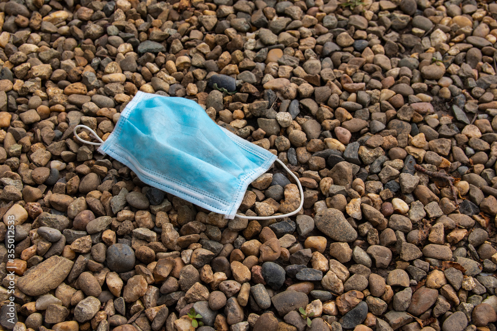 A used blue medical mask is cast on the ground. Effects of quarantine after a virus. A used blue medical mask is cast on the ground. Effects of quarantine after a virus.