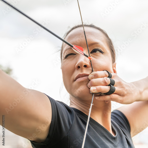 attractive woman on archery, focuses eye target for arrow from bow