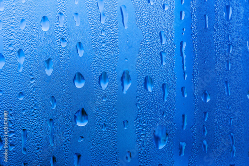 Macro photography of water drops on glass window blue background after the rain