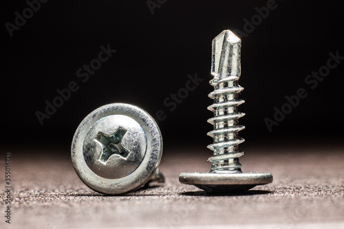 Fotografie Self drilling screws with a washer for metal on a wooden surface