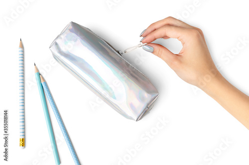 Woman's hand with manicure holding pencil case on blue background photo