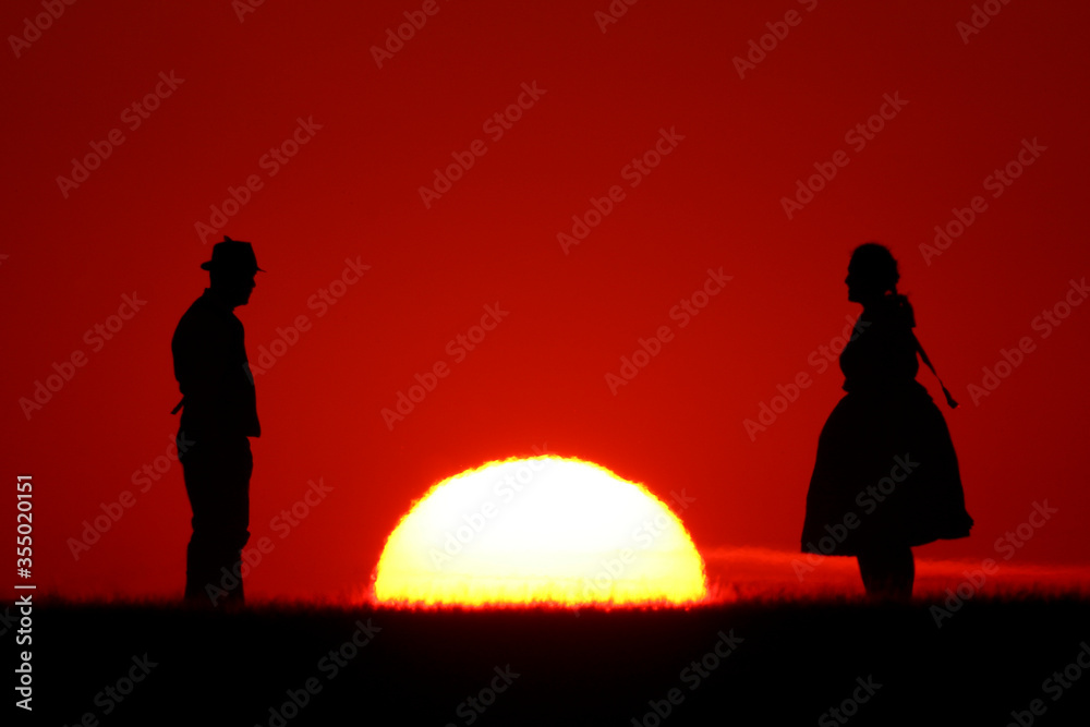 Silhouette of a young couple at sunset. in the middle of the setting sun.