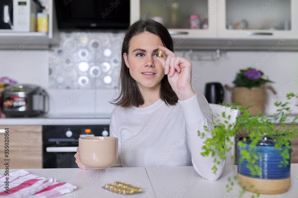 Young beautiful woman taking pill vitamin a, d, e, fish oil, omega-3