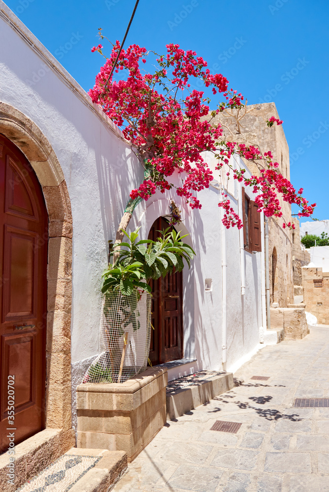 Greek street with spring flowers on Rhodes island. Lindos village, Dodecanese, Greece.