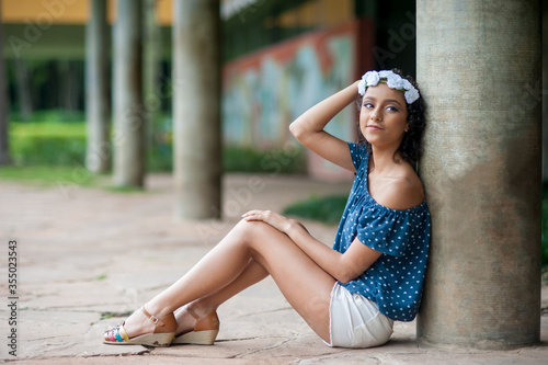 teenager brazilian girl leaning on a pilaster sitting on the floor. Copy space