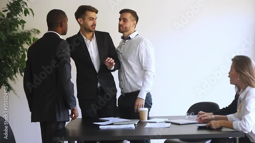 During multi-ethnic partners meeting negotiations european and african businesspeople having conflict, fighting, showing aggression negative attitude, racial discrimination unfair treatment concept photo