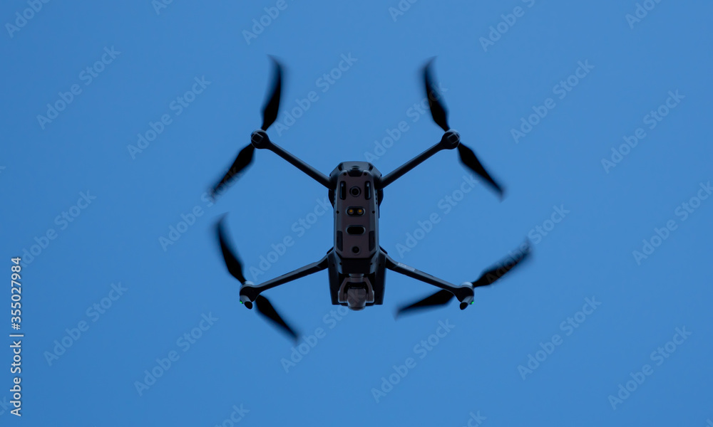 matt black generic drone flying free in the blue sky matt black generic drone flying free in the blue sky