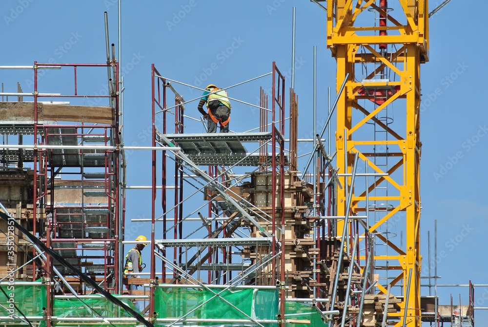 MELAKA, MALAYSIA -APRIL 6, 2016: Construction workers wearing a safety harness and adequate safety gear while working at a high level at the construction site in Melaka, Malaysia.