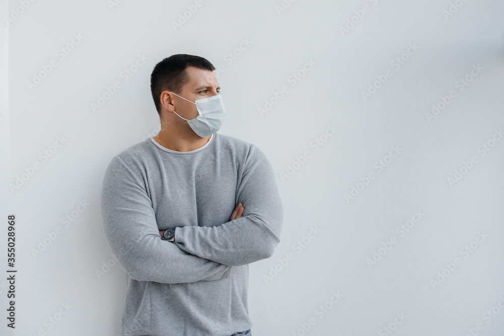 A young man stands on a gray background wearing a mask during a quarantine with free space. Quarantine in the mask A young man stands on a gray background wearing a mask during a quarantine with free space. Quarantine in the mask