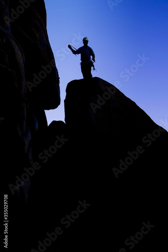 Silhouette of Rock Climber  with hard hat hold rope on rocks