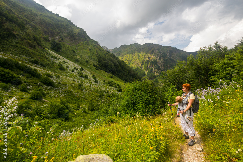 Woman Hiker trekking in mountains with child in backpack . 