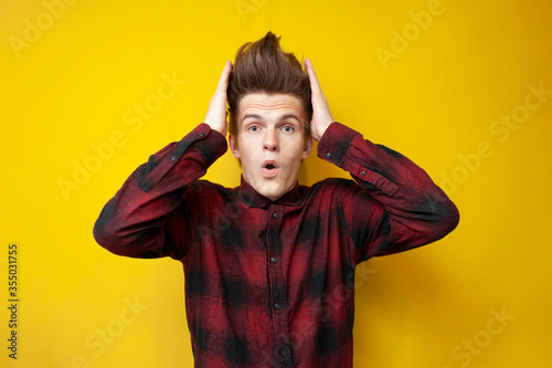 crazy guy with a funny hairstyle is surprised on a yellow isolated background, hipster with strong hair styling is shocked © Богдан Маліцький