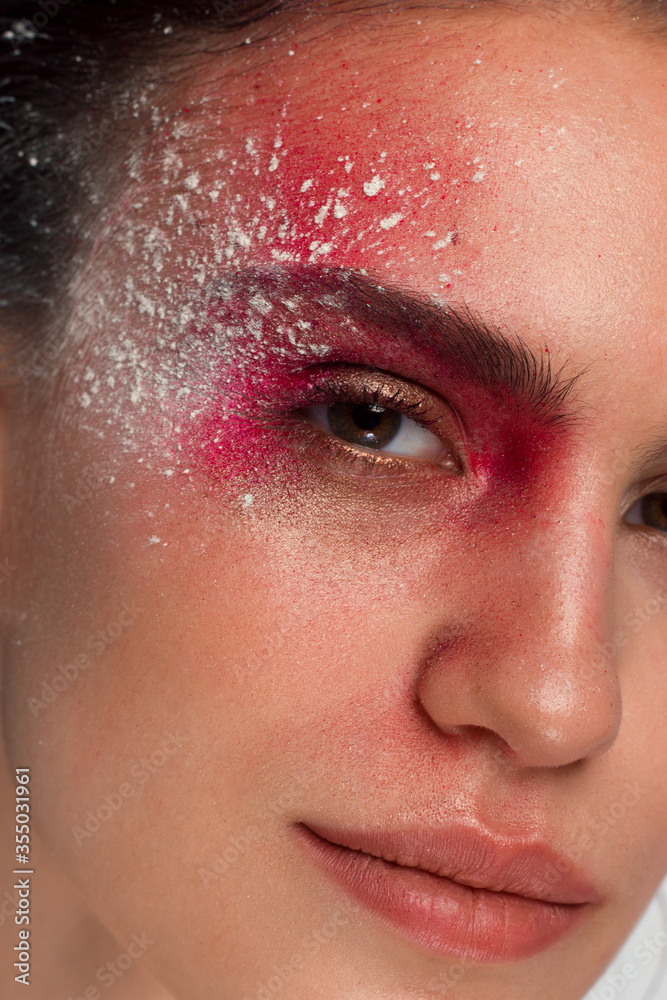 The fashionable photo of the young woman with creative cosmetics on a beautiful face. Space, spangles and multi-colored pigments in cosmetology. A make-up for Halloween, a carnival