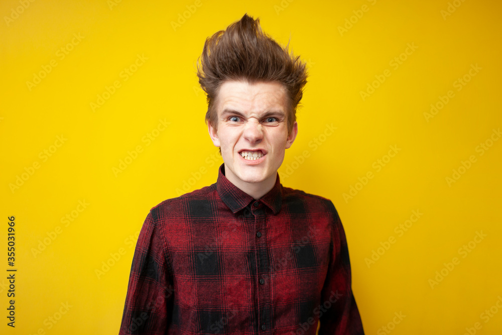 aggressive guy gets angry and looks on a yellow isolated background, annoyed man, close-up aggressive guy gets angry and looks on a yellow isolated background, annoyed man, close-up