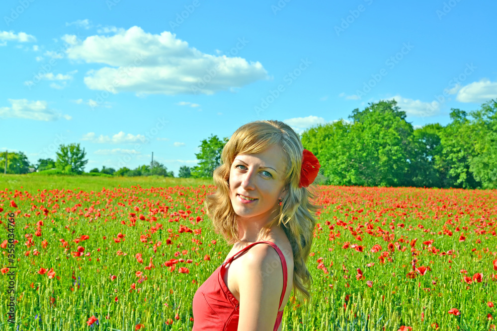 Φωτογραφία A young woman with red poppy in her hair stands in a poppy field