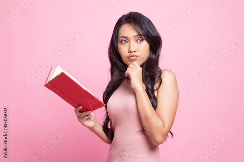 Young Asian woman with a book is thinking.