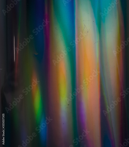 Holo background with multiple colors. Fantasy rainbow texture. Real photo flash hitting curved holographic foil. 