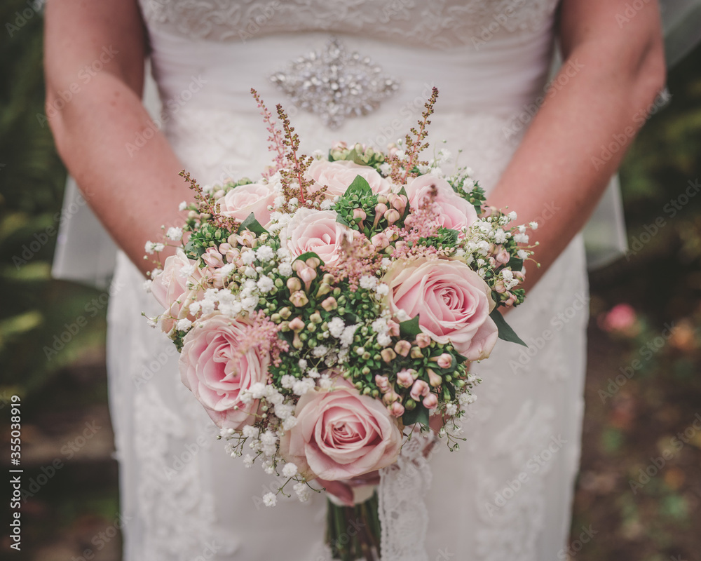 Φωτογραφία Bride holds her wedding bouquet against her dress