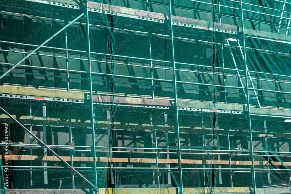 scaffolding covered in green mesh. Construction or repair work. perspective view.