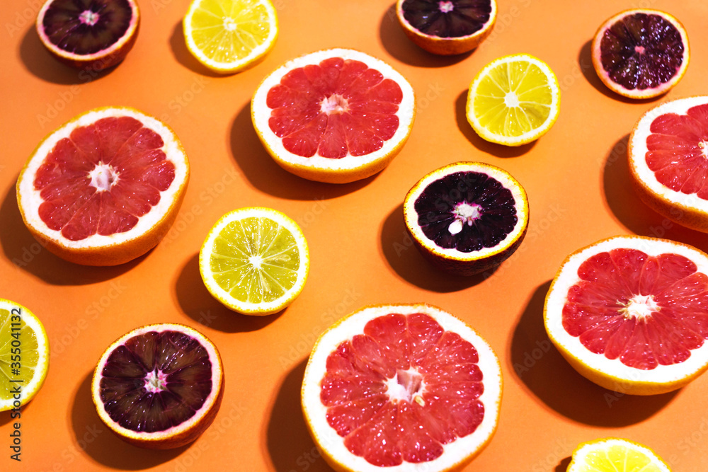 Many variety citrus fruits pattern in sunlight on orange background in angle. Summer grapefruit orange lemon juice or healthy food concept. Banner design template, wallpaper with trendy hard shadow Many variety citrus fruits pattern in sunlight on orange background in angle. Summer grapefruit orange lemon juice or healthy food concept. Banner design template, wallpaper with trendy hard shadow