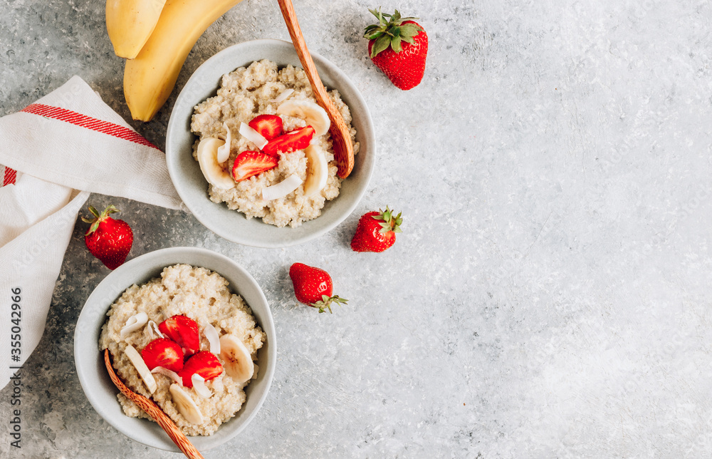 Quinoa porridge with coconut milk and fresh strawberries on light gray background. Healthy Lactose and Gluten Free Breakfast.