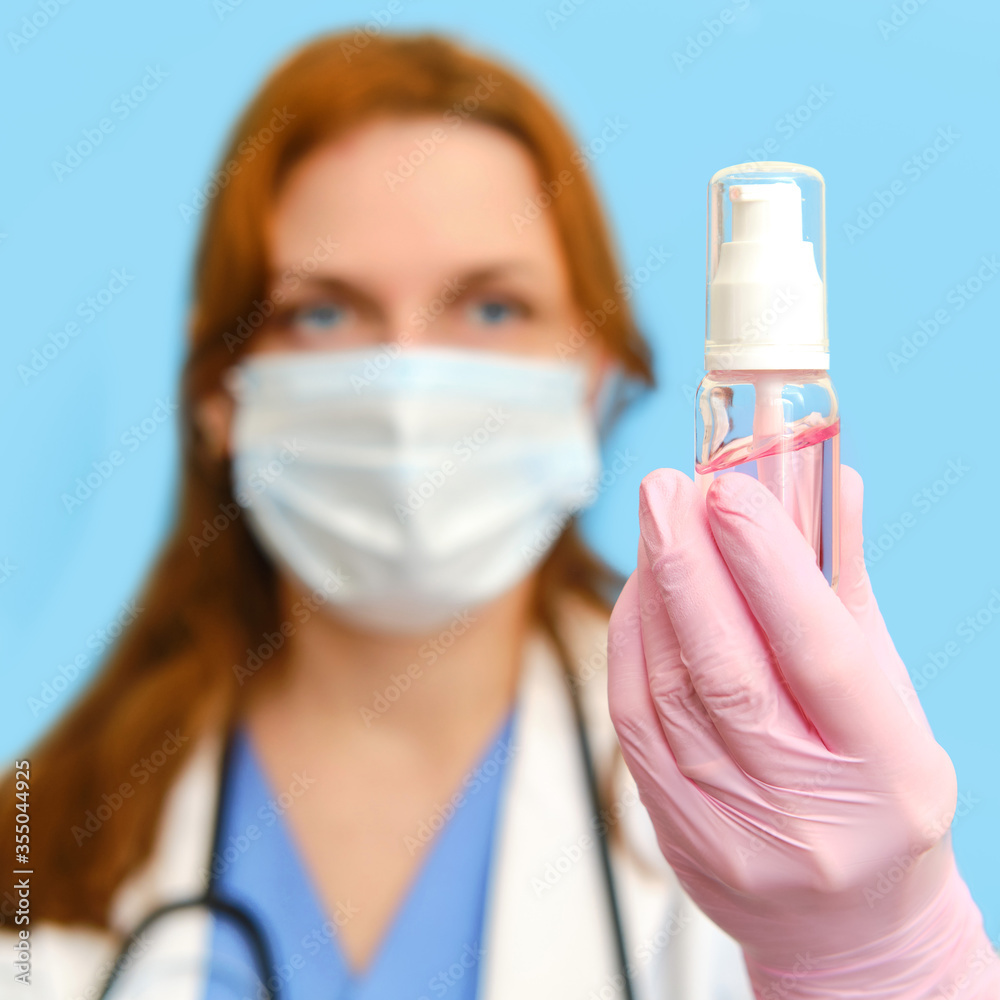 Woman nurse with sanitizer for disinfection on a blue background, face closeup. Woman nurse with sanitizer for disinfection on a blue background, face closeup.