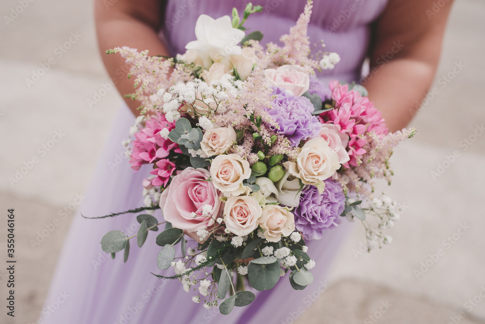 close up of bridesmaid in lilac dress holding flowers