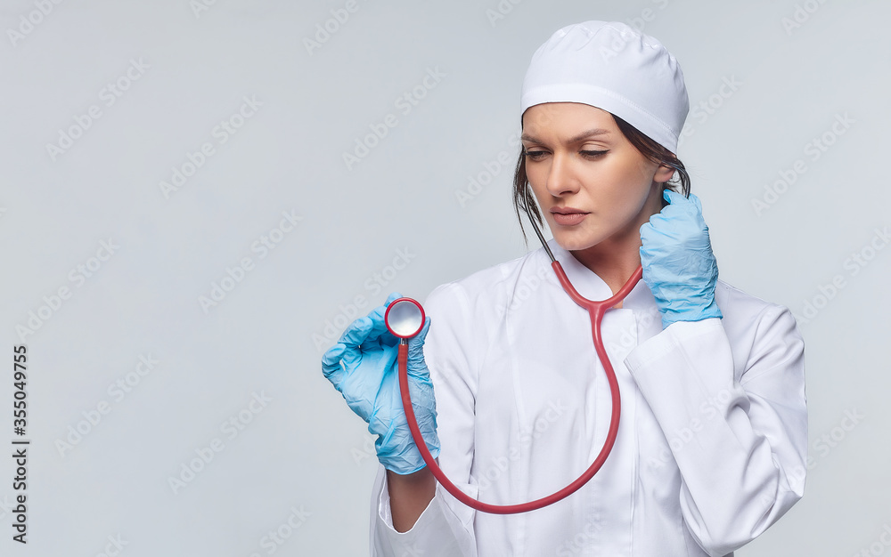 Medical concept of a female doctor in a white coat with a stethoscope, doctor. A female hospital worker looks at the camera and smiles, Studio, White background