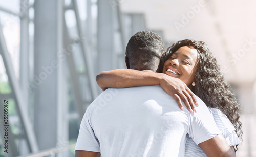 Long-awaited meeting. Happy african american woman embracing her husband in airport