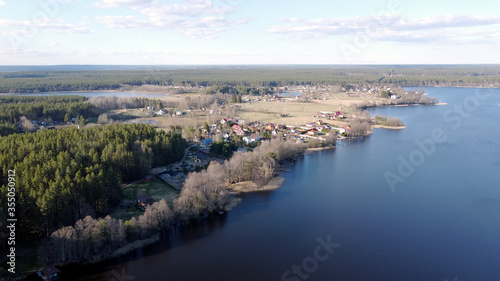 Aerial view of the lake Borisovskoye, the forest and the settlement in autumn day, Borisovo, Leningrad Oblast, Russia