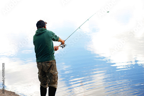 adult man fishing on a lake in cloudy weather
