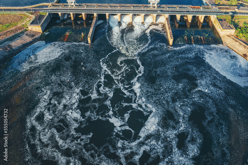 Hydroelectric dam or hydro power station at water reservoir, aerial view from drone. Draining water through gate, hydropower.