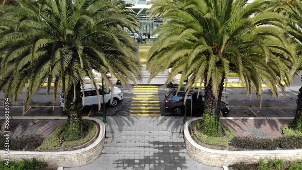 Acercamiento a la entrada exterior de un hotel. Un vehículo arranca.