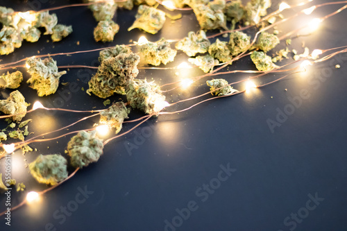 Dried cannabis flower with twinkly lights on a dark background.
