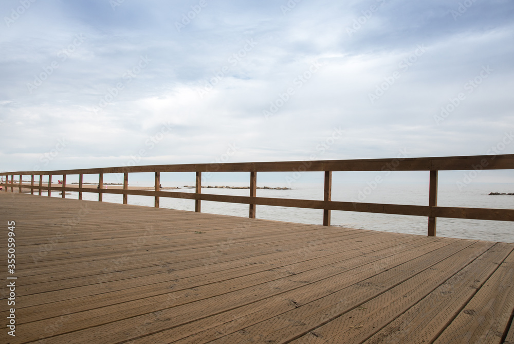 a wooden fence at a boardwalk at the seaside with the sea visible in the background