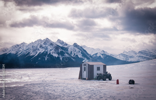 Ice shack sitting on Lake Abraham in Alberta with a quad and the peaceful mountains in the distance photo