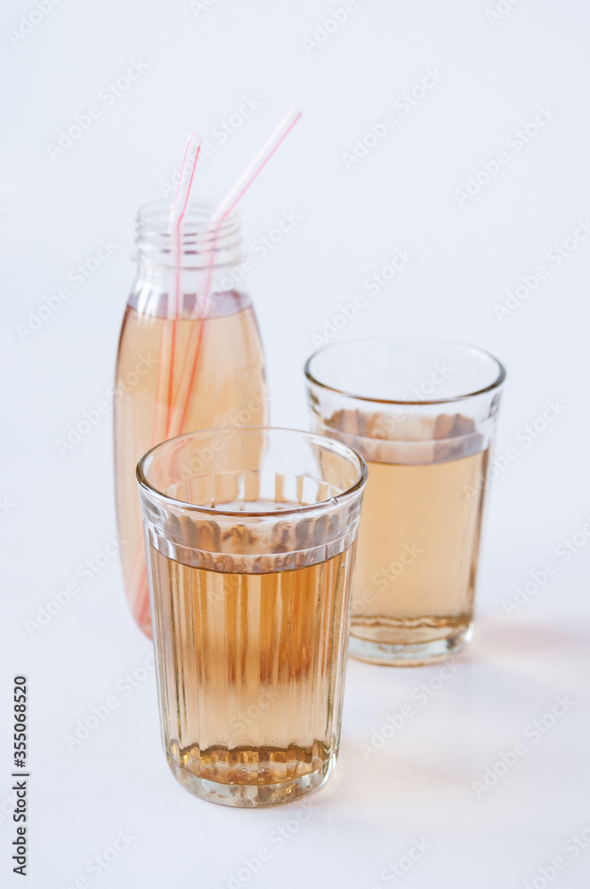 Two glasses and a bottle with Apple juice tubes on a white background Two glasses and a bottle with Apple juice tubes on a white background