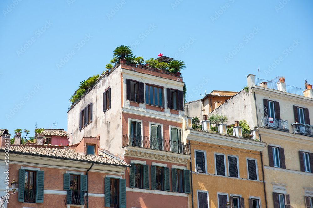 Lively and vibrant italian rooftops of Rome in front of clear light blue sky.