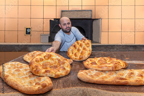  A baker making Turkish pita bread. Baker taking fresh Turkish pita bread from oven. Manufacturing process of  Turkish Ramadan Pita. photo