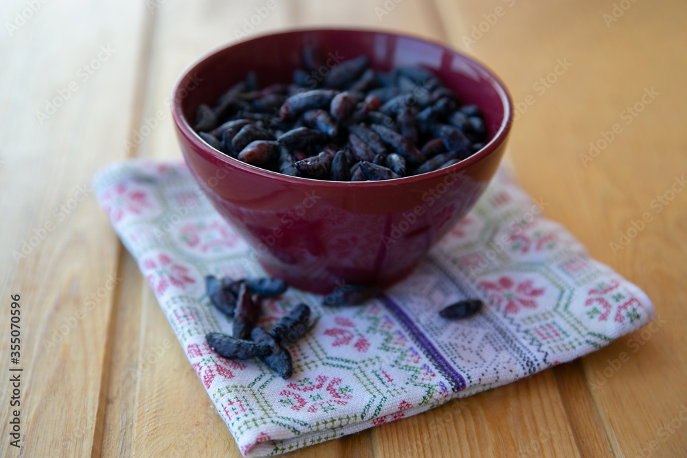 honeysuckle berries in a maroon Cup with a brown towel on the wooden table
honeysuckle berries in a maroon Cup with a brown towel on the wooden table