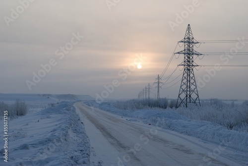 The road along the high-voltage power line on a cold December morning. Khanty-Mansiysk. Western Siberia. Russia.