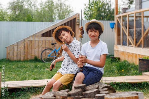 Children getting helpings of food from barbecue grill, Children grilling meat. Family camping and enjoying BBQ. barbecue preparing steaks, kebab. Kids eating grill and healthy 