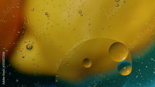 High quality abstract close-up 4k slow motion video of a bright colourful natural bacground with lemons and oranges giving orange blue and yellow colours with the water and oil bubbles moving around