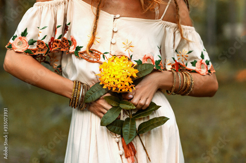 close up of woman hands holding yeloow flower outdoors photo