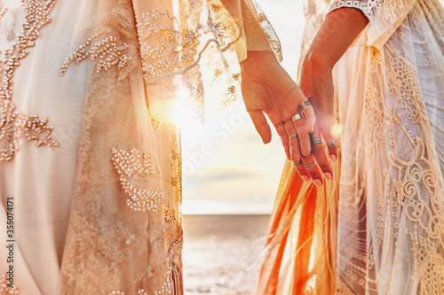 two beautiful young woman in elegant boho dresses oudoors at sunset photo