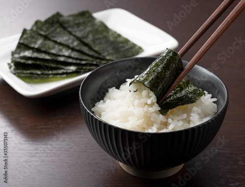 Wrapping nori around rice set against a wooden backdrop. photo